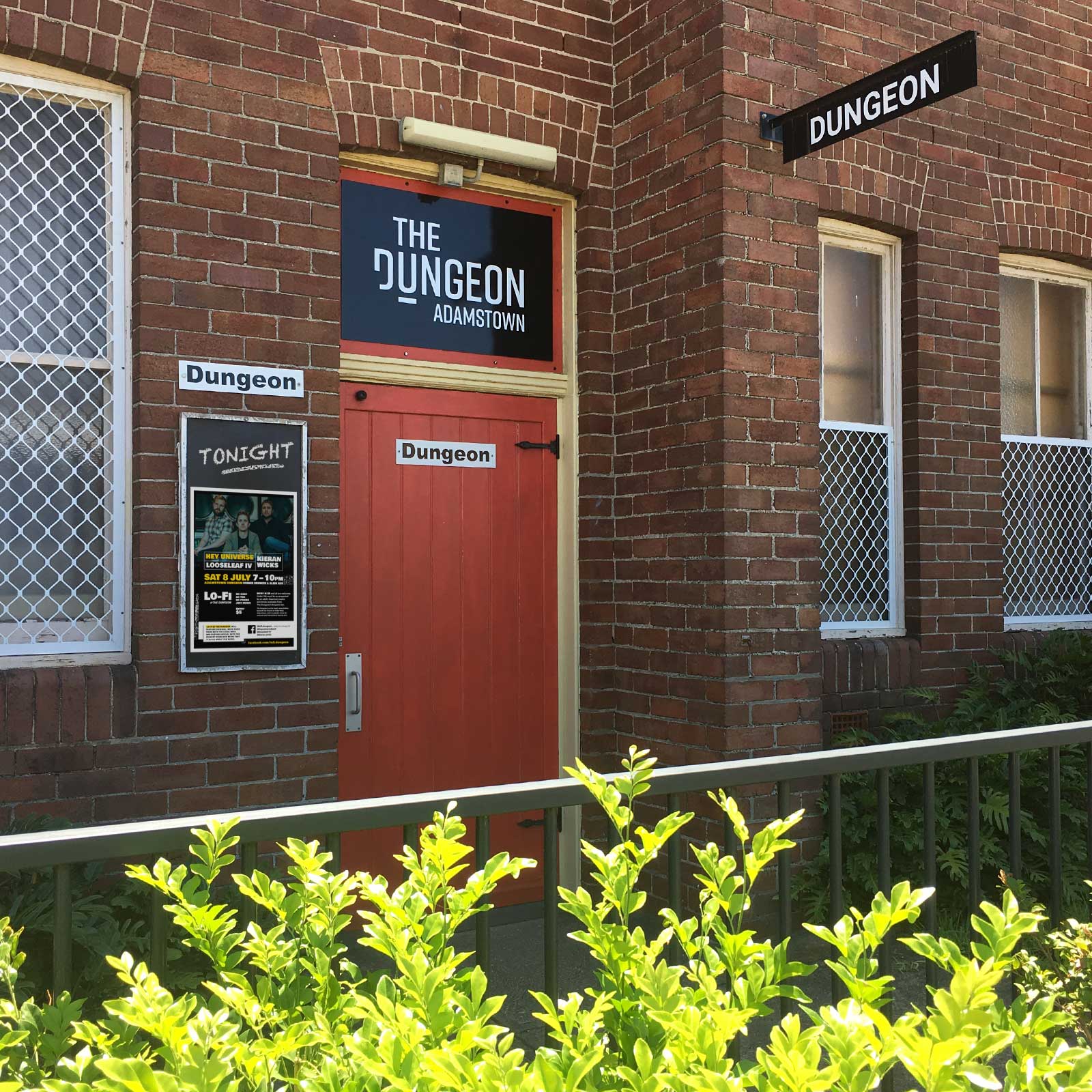 Dungeon logo signage above red door.